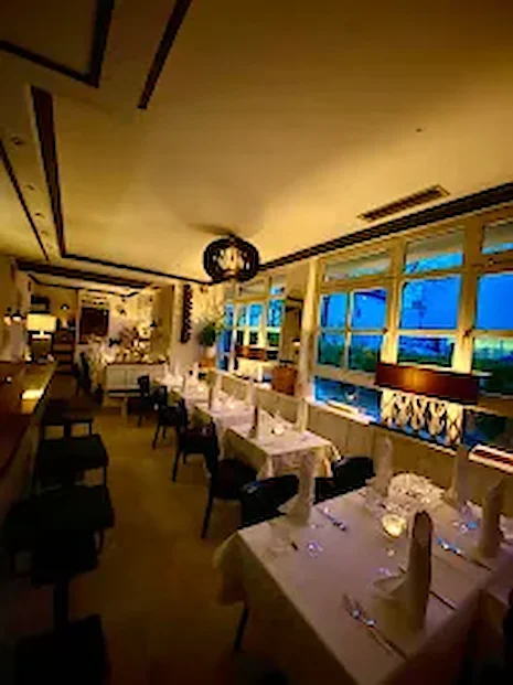 Eleganter Innenraum am Abend mit weißen Tischdecken und Pendelleuchten — Ristorante Risotto München